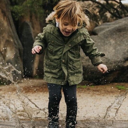 girl in green jacket standing on water