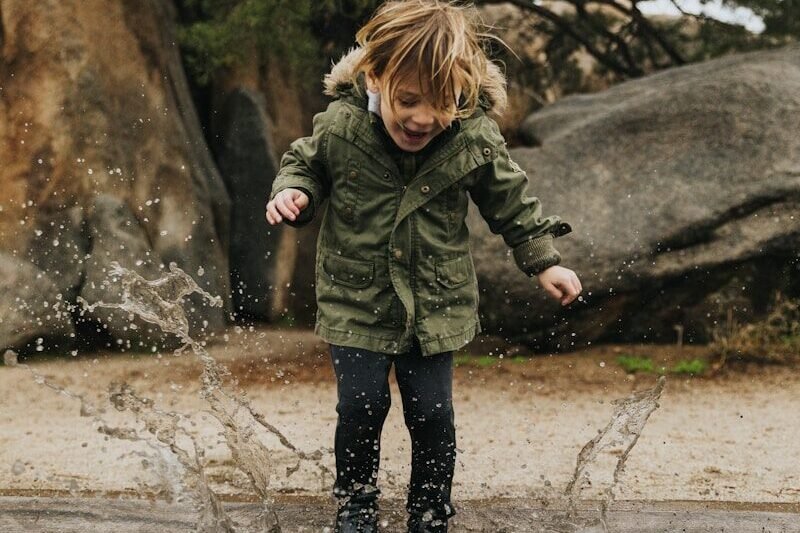 girl in green jacket standing on water