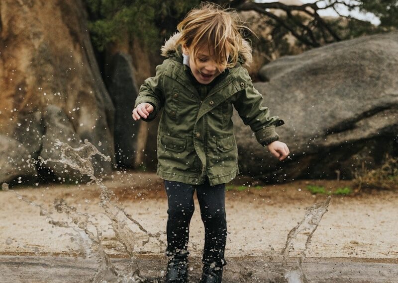 girl in green jacket standing on water