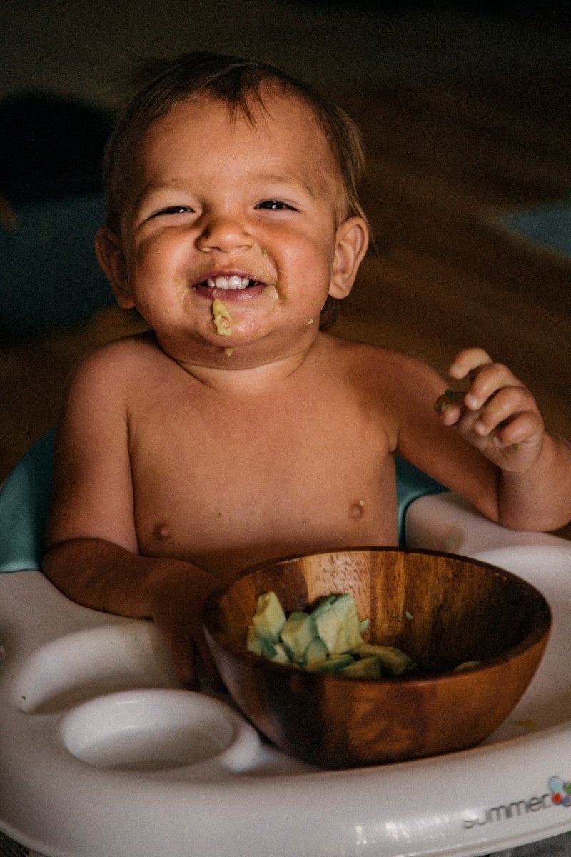 toddler eating vegetable in bowl