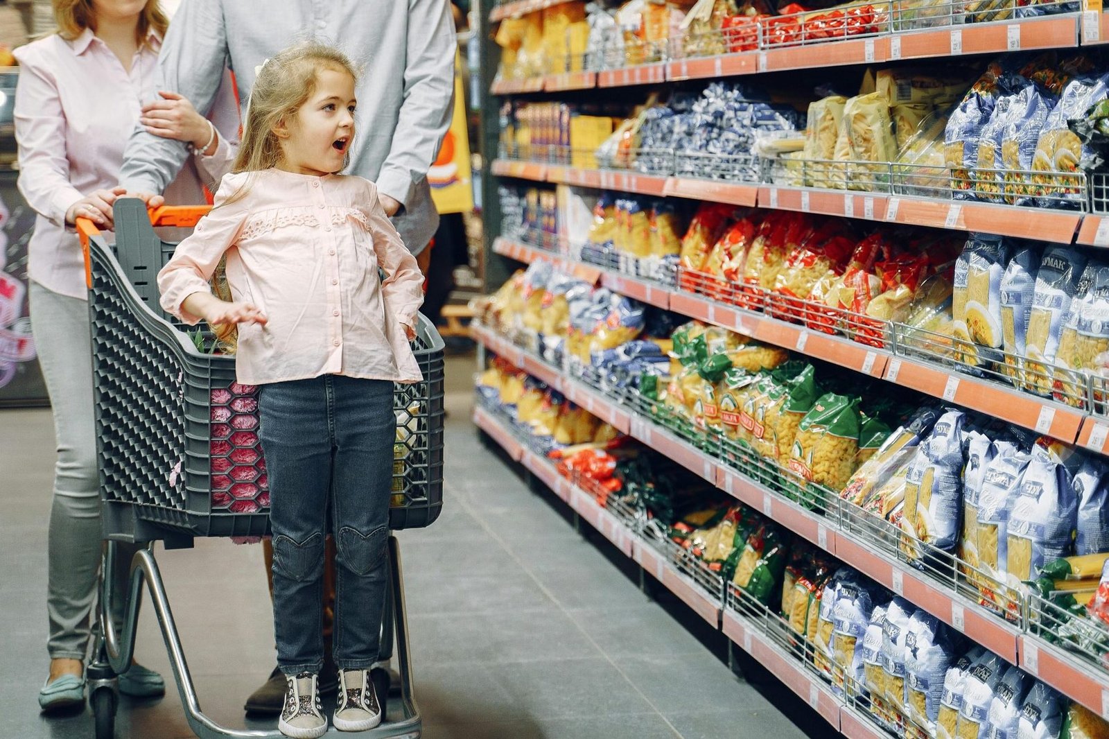 Ein kleines Kind steht in einem Supermarkt und schaut auf die Regale mit Süßigkeiten. Es wirkt enttäuscht, da es keine Süßigkeiten bekommt.